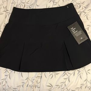 Pleated woven skort in black with a stash pocket on the inside of the skirt.